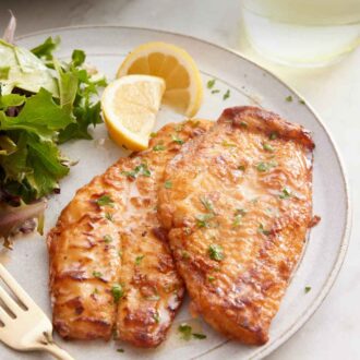 Pinterest graphic of a plate with sole meunière with two lemon wedges and a side of mixed greens.