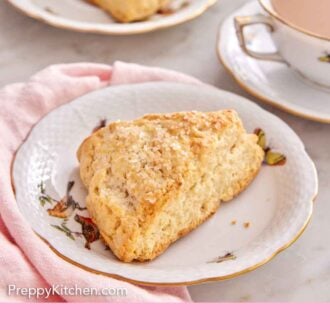 Pinterest graphic of a plate with a scone in it with a cup of coffee and second scone in the background.