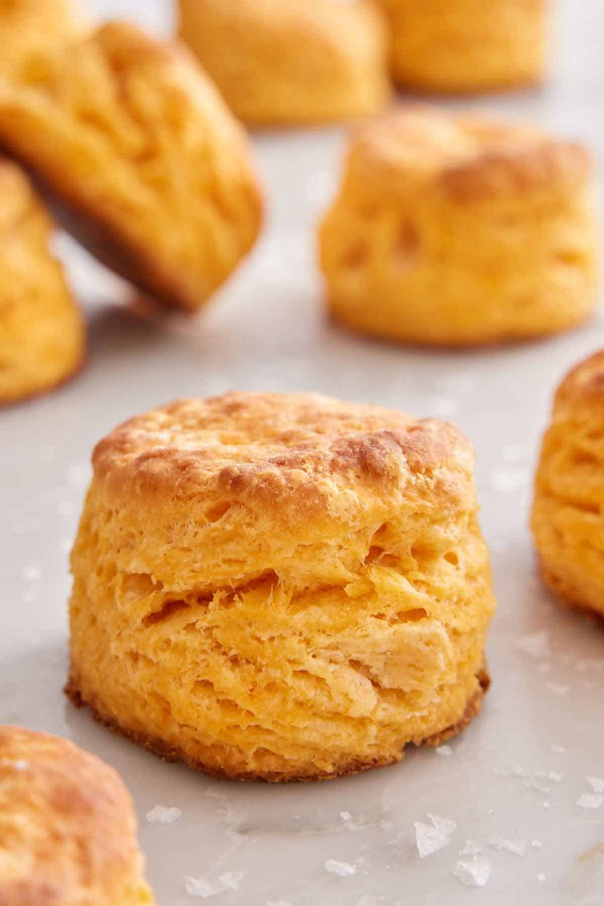 A sweet potato biscuit on a marble counter with additional biscuits in the background.