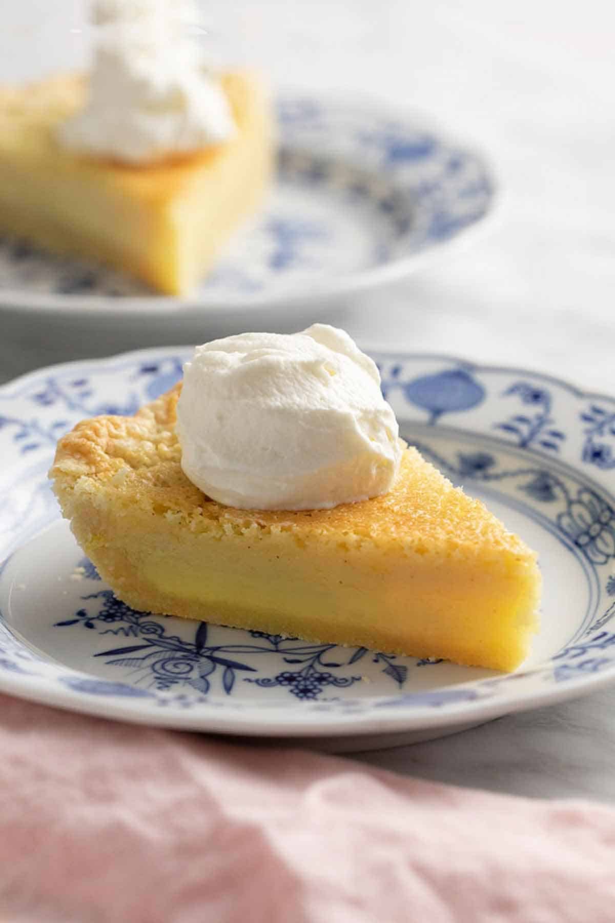 Two slices of buttermilk pie on blue and white plates. One in the background out of focus.