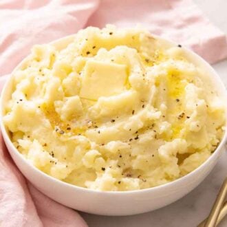 A bowl of mashed potatoes with pepper, melted butter, and a pat of butter on top.