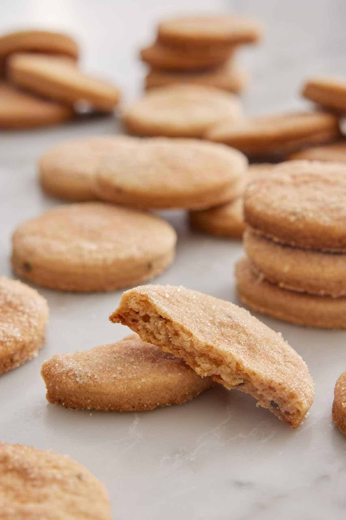 Multiple biscochitos with the one in the front broken in half, showing the interior.