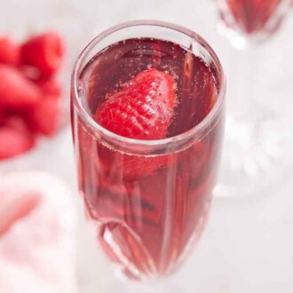 A glass of Kir Royale with a raspberry.