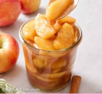 Pinterest graphic of apple pie filling spooned into a jar. Apples in the background.