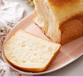 Pinterest graphic of a platter with a loaf of milk bread with a slice cut in front.