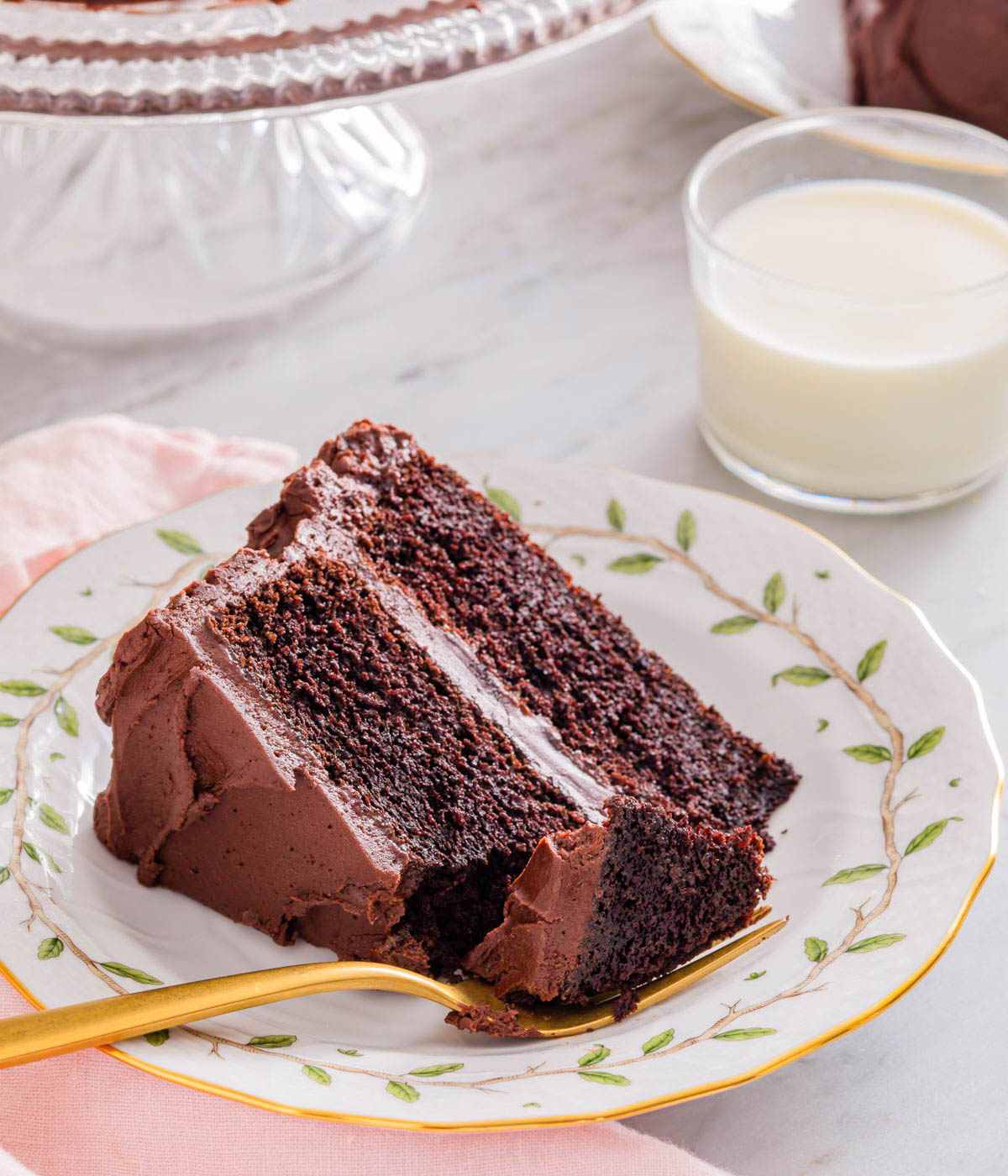 A slice of devil's food cake on a plate with a forkful taken out.