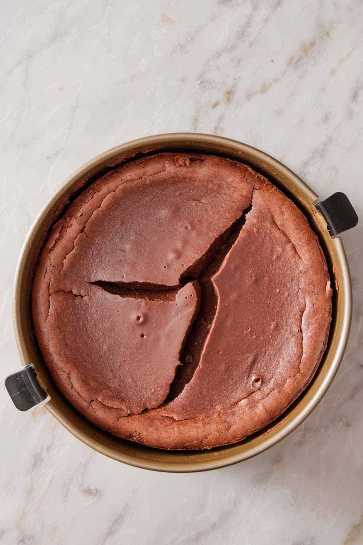 Overhead view of a cracked chocolate cheesecake.