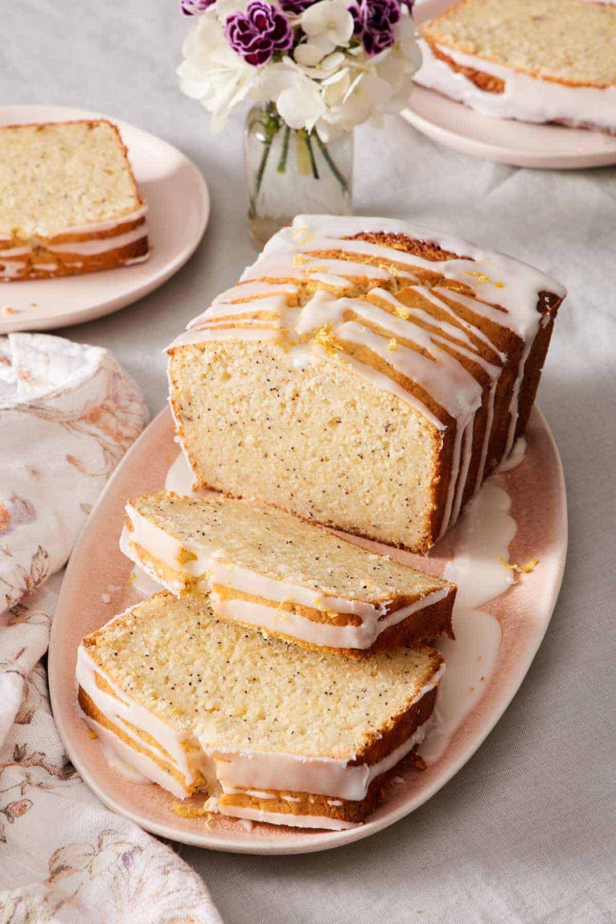 Lemon poppy seed loaf on a platter with a few slices cut out.