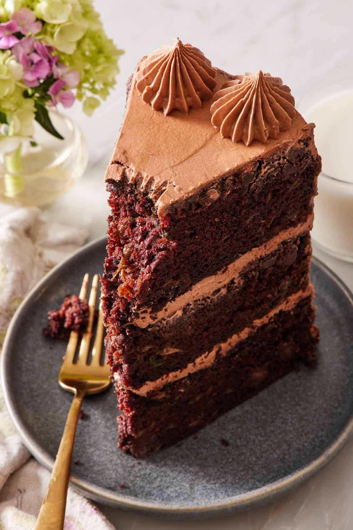 Close-up of a slice of chocolate zucchini cake on a small plate with a small forkful removed.