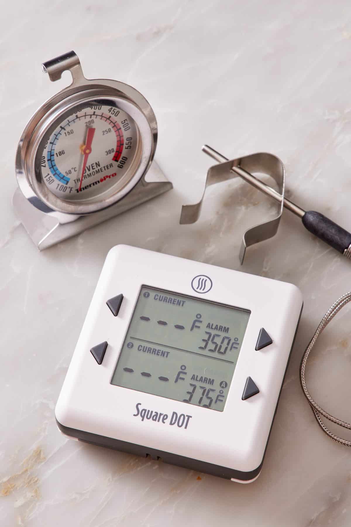 Oven thermometers on a marble countertop.