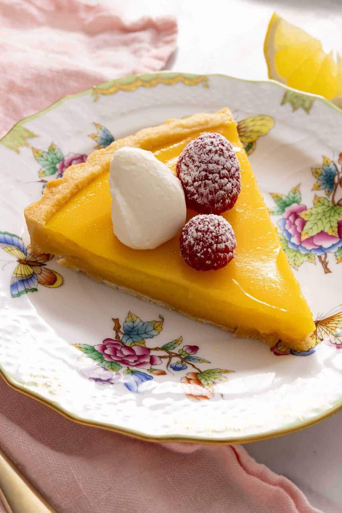 Close-up of a slice of lemon tart on a patterned plate.