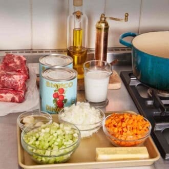 Pinterest graphic showing mise en place with chopped vegetables, canned tomatoes, oil, and beef.